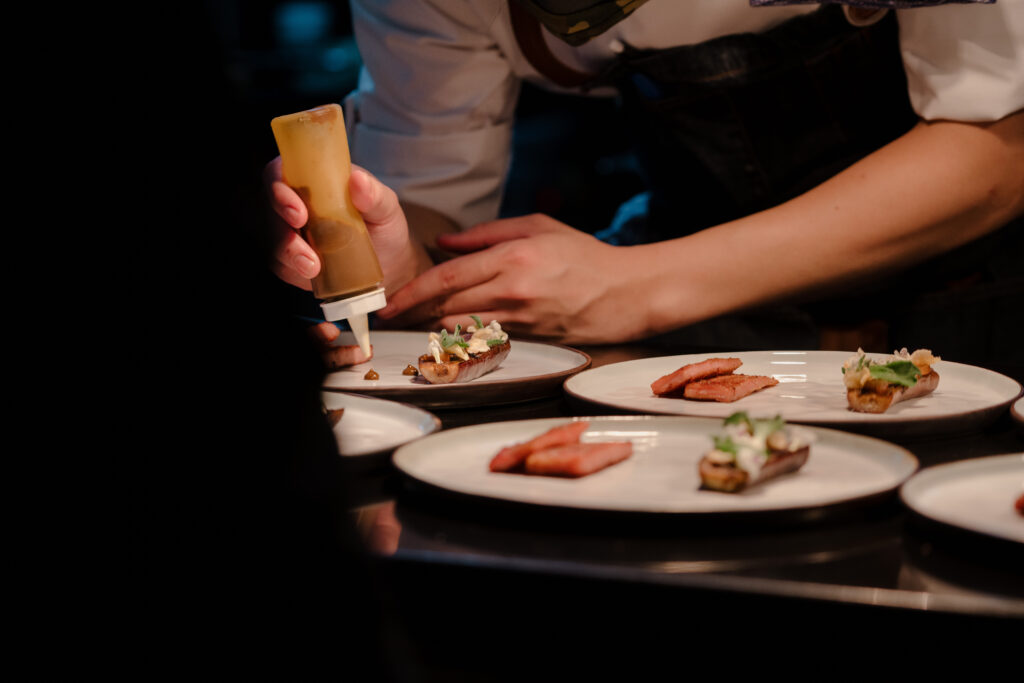 Chef plating gourmet dishes at a luxury catering event with refined presentation and seasonal ingredients